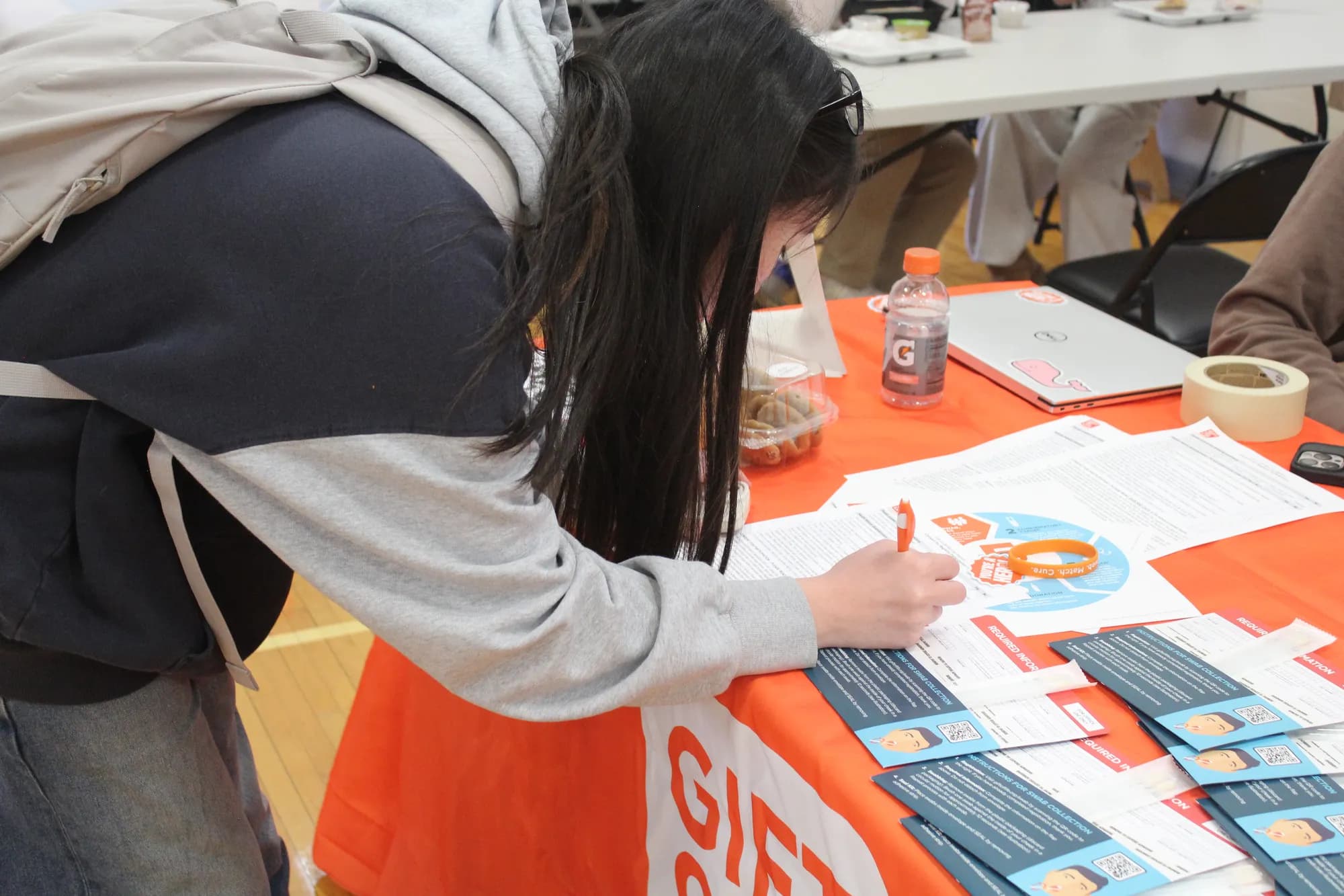 A student filling out a registry form at a swab drive